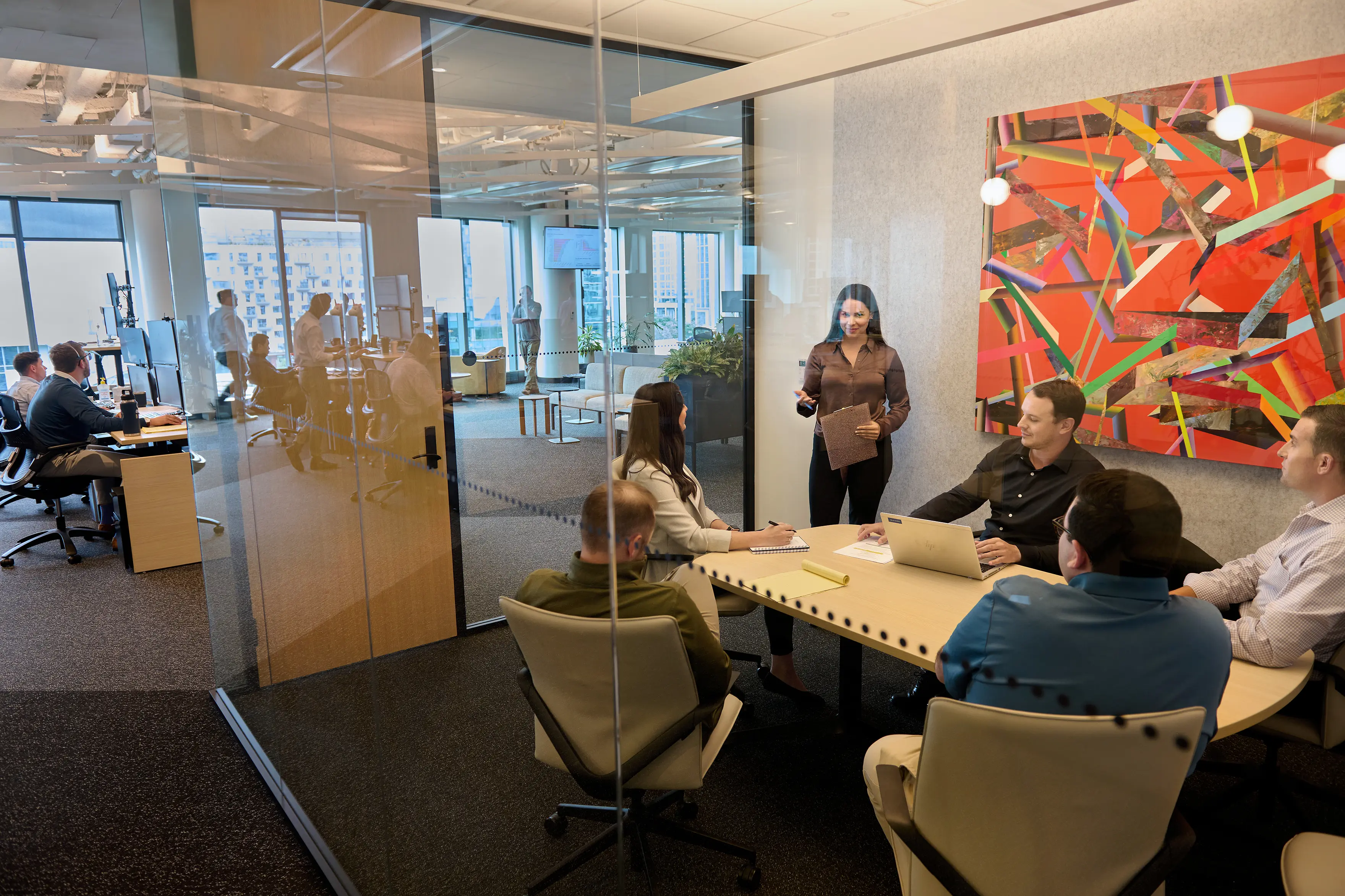 Team meeting and collaborating in a glass office with abstract orange artwork in the background